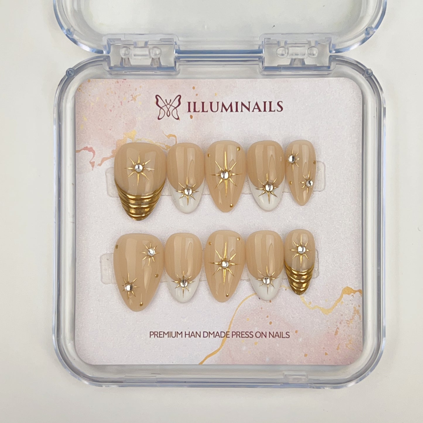 Set of press-on nails with gold and beige design in a clear case, featuring the brand 'Illuminails'.