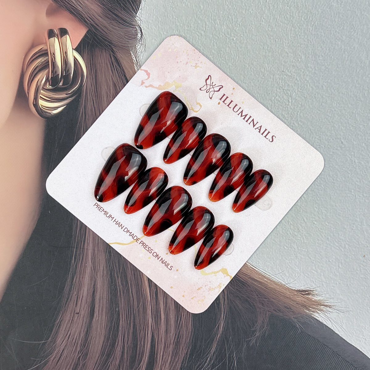 Crimson Tortoise glossy red and black press-on nails shown at an angle