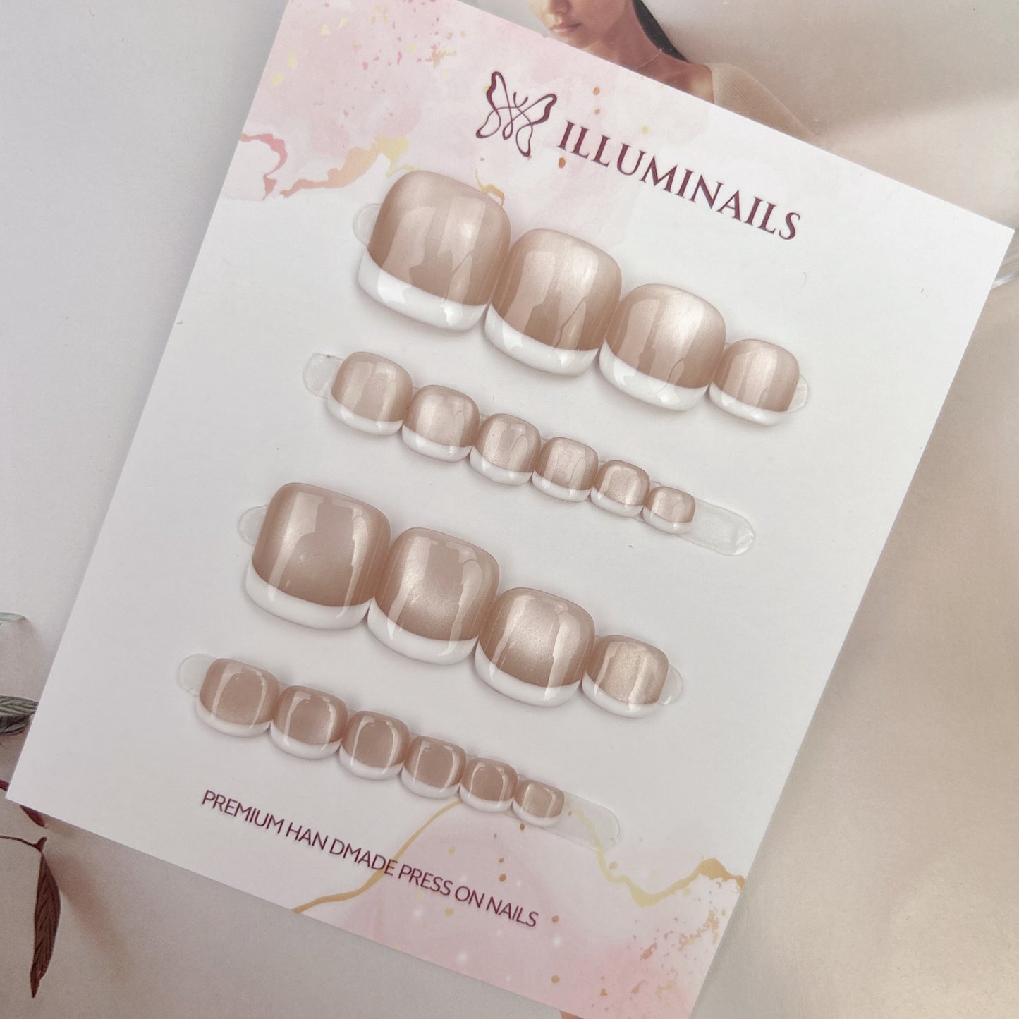 White French cat eye press-on toenails photographed on a neutral lifestyle background
