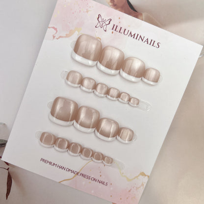White French cat eye press-on toenails photographed on a neutral lifestyle background